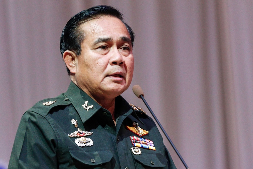 General Prayut Chan-o-cha, wearing a military uniform, talks into a microphone.