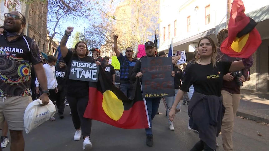 A row of people holding a sign and flags