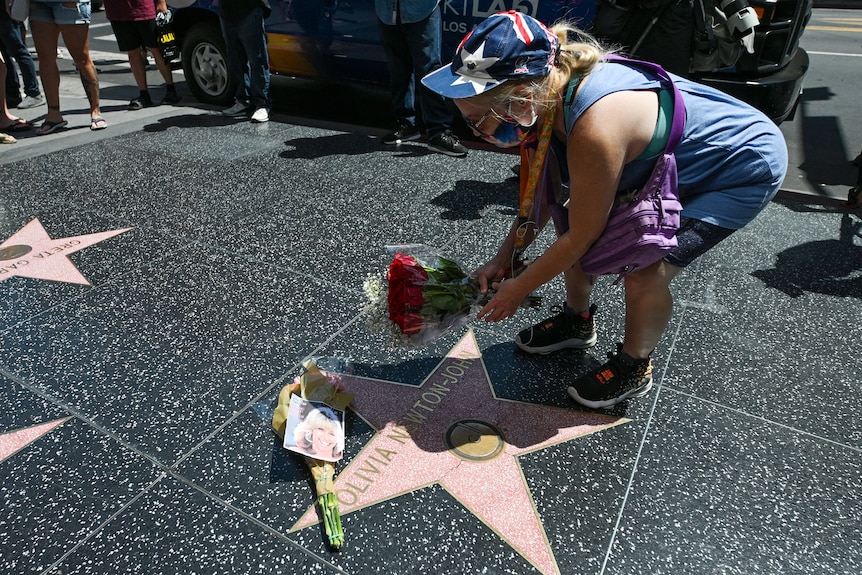 A woman laying flowers on the Olivia Newton-John star on the Hollywood walk of fame. 