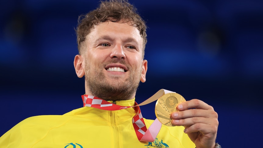 Australia's Dylan Alcott smiles while he holds his Paralympic gold medal in wheelchair tennis.