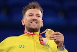 Australia's Dylan Alcott smiles while he holds his Paralympic gold medal in wheelchair tennis.