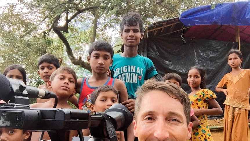 James Bennet takes a selfie with a group of young people in Bangladesh standing behind him
