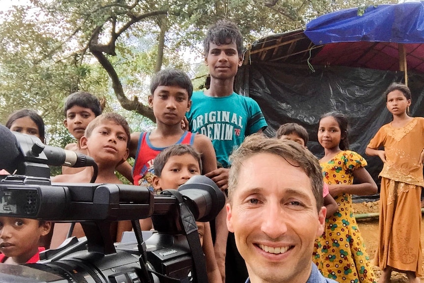 James Bennet takes a selfie with a group of young people in Bangladesh standing behind him