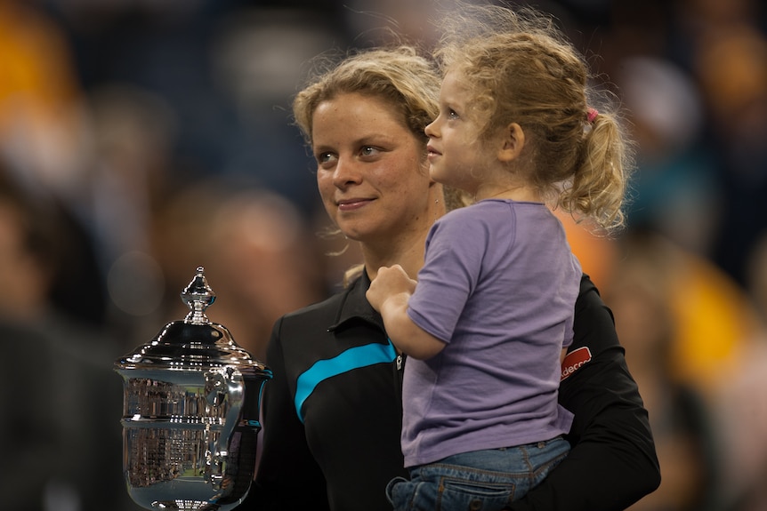 A Belgian female tennis player holds her daughter along with the 2010 US Open trophy.