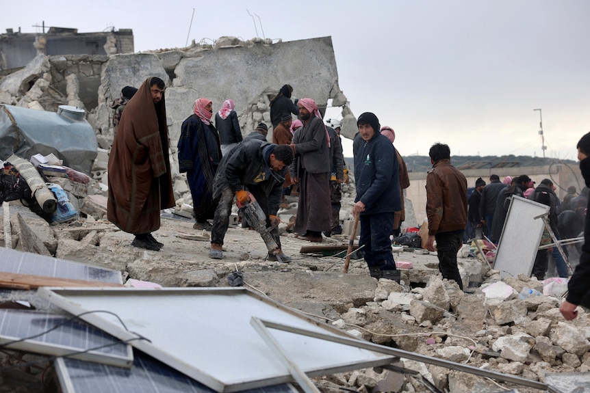 People stand among rubble working to clear it. 