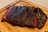 Sliced rare steak on a wooden chopping board.