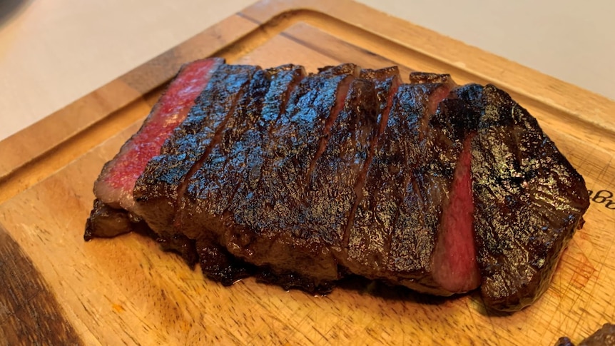 Sliced rare steak on a wooden chopping board.