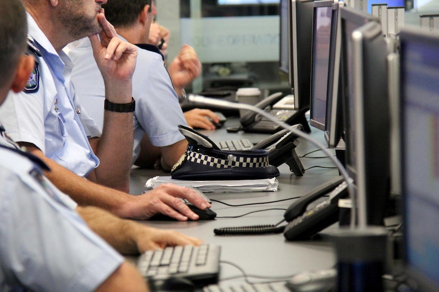 Faceless police officers in uniform in front of computers.