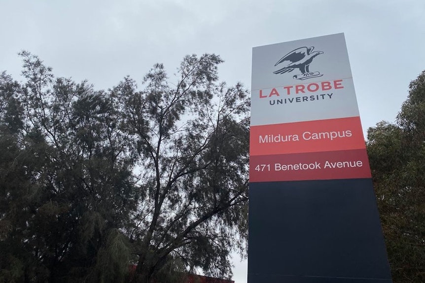 a la trobe mildura campus sign  red and white in colour with trees in the background and grey sky