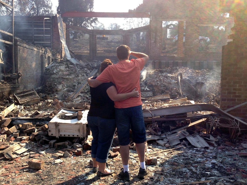 Residents comfort each other after returning to their burnt-out home at Winmalee.