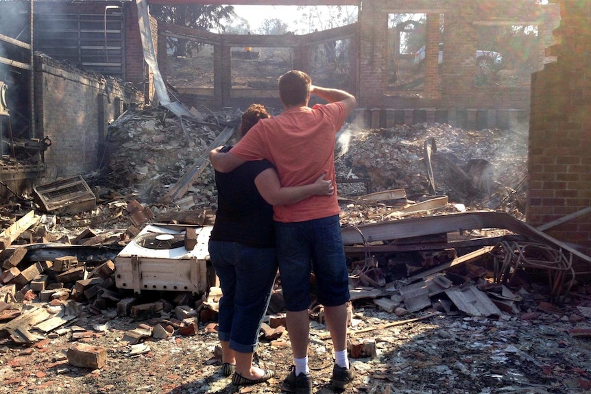 Residents comfort each other after returning to their burnt-out home at Winmalee.