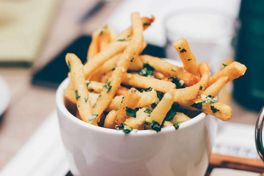 Salty chips in bowl with sprinklings of herbs