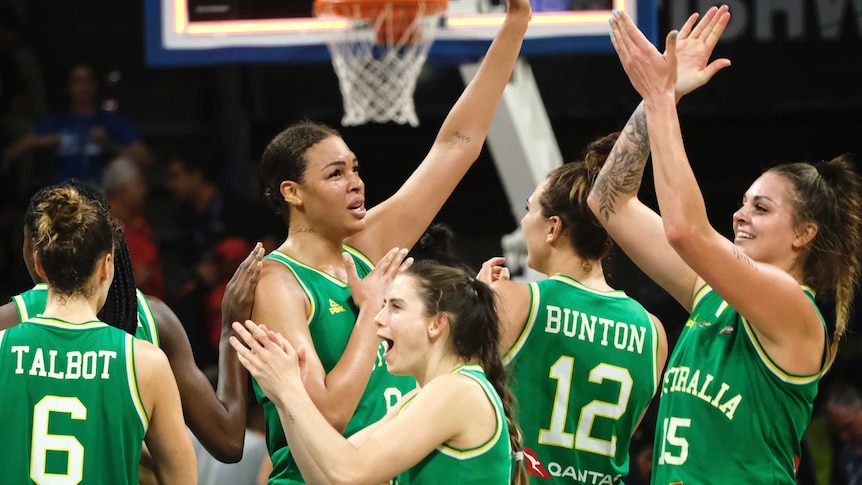 Women wearing green singlets high five each other.