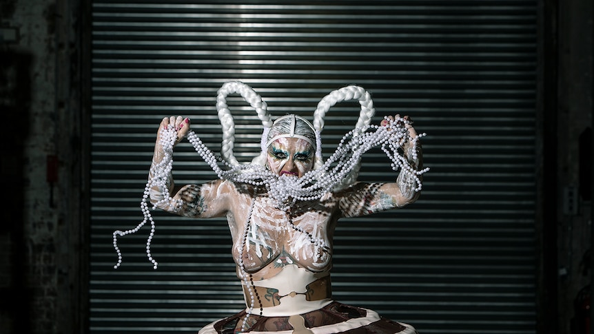 Colour photo of burlesque and performance artist Glitta Supernova performing on stage.