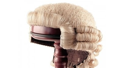 A barrister wig on a wooden stand.