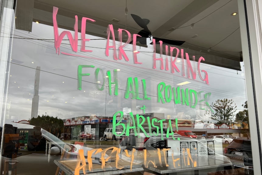 A paint pen sign on a window reads: WE ARE HIRING FRONT OF HOUSE ALL ROUNDER AND BARISTA!