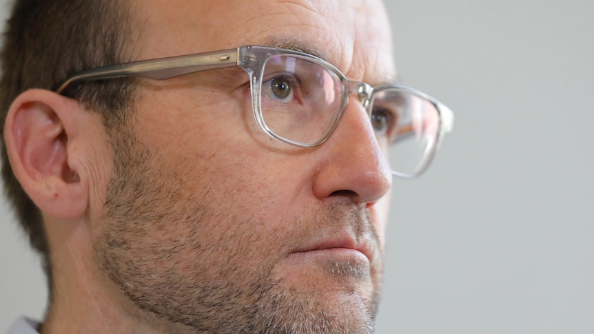 A close shot of Bandt's face, looking serious and wearing glasses.