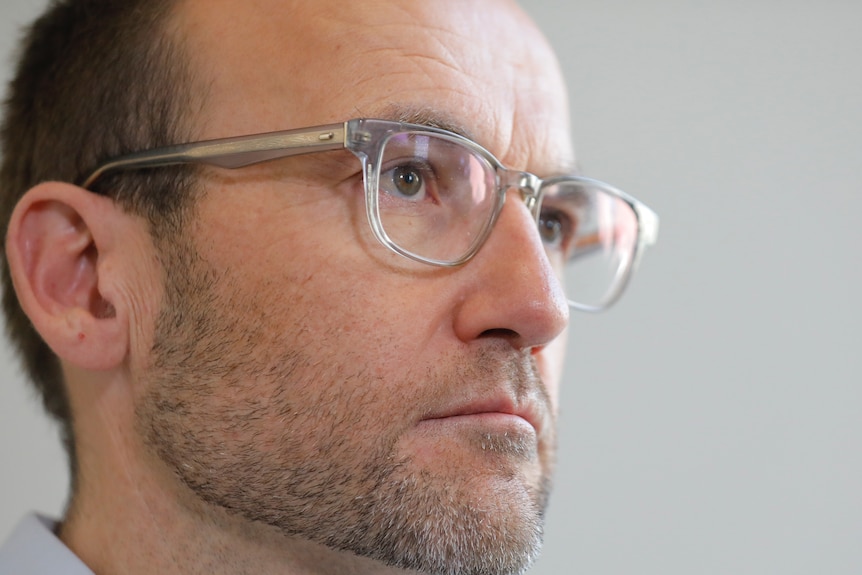 A close shot of Bandt's face, looking serious and wearing glasses.