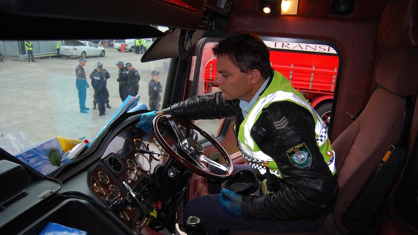 A police officer inspects the cab of a truck during a raid on the headquarters of Lennons Transport Services