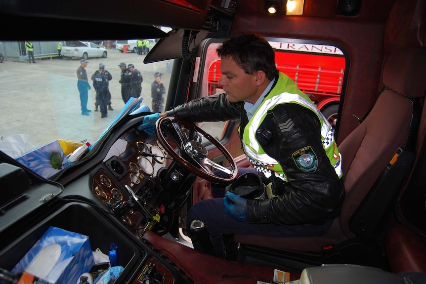 A police officer inspects the cab of a truck during a raid on the headquarters of Lennons Transport Services