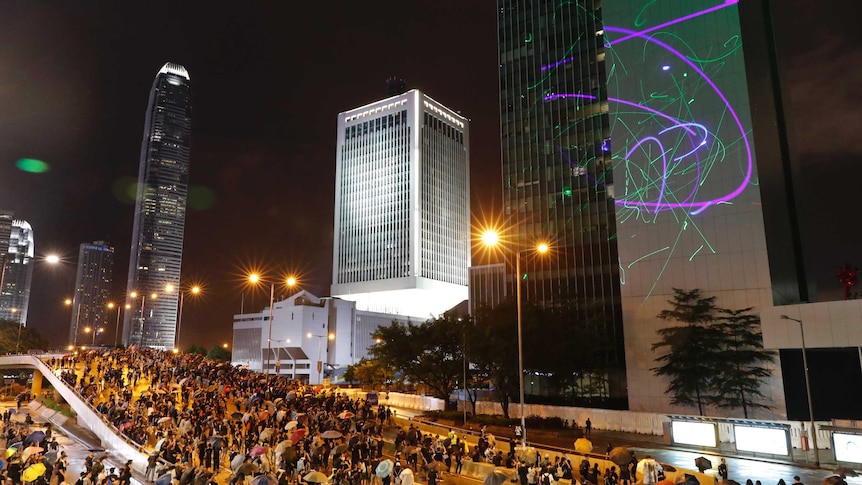 A group of protestors light up a skyscraper with lasers at night