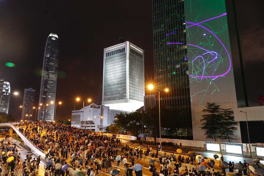 A group of protestors light up a skyscraper with lasers at night