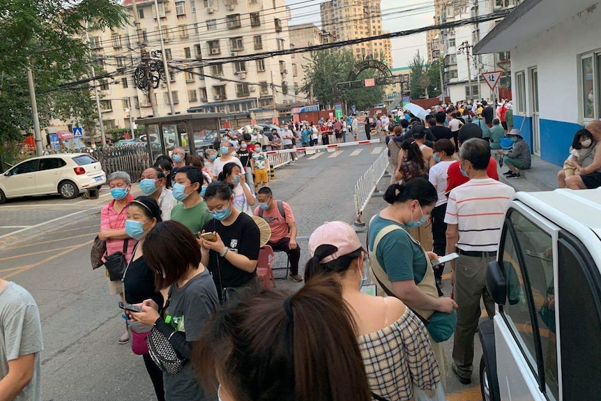 Big lines are visible along the street with people waiting for a coronavirus test. They are all wearing masks.