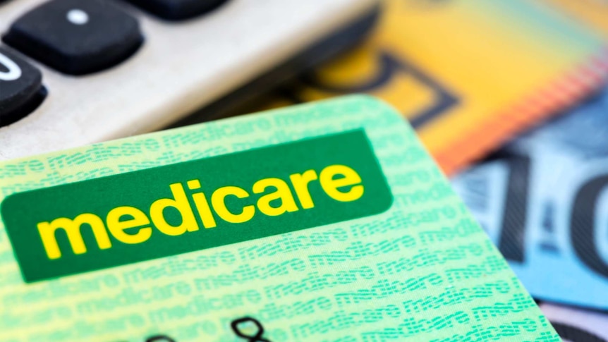 Close-up of a green Medicare card with a calculator and money in the background