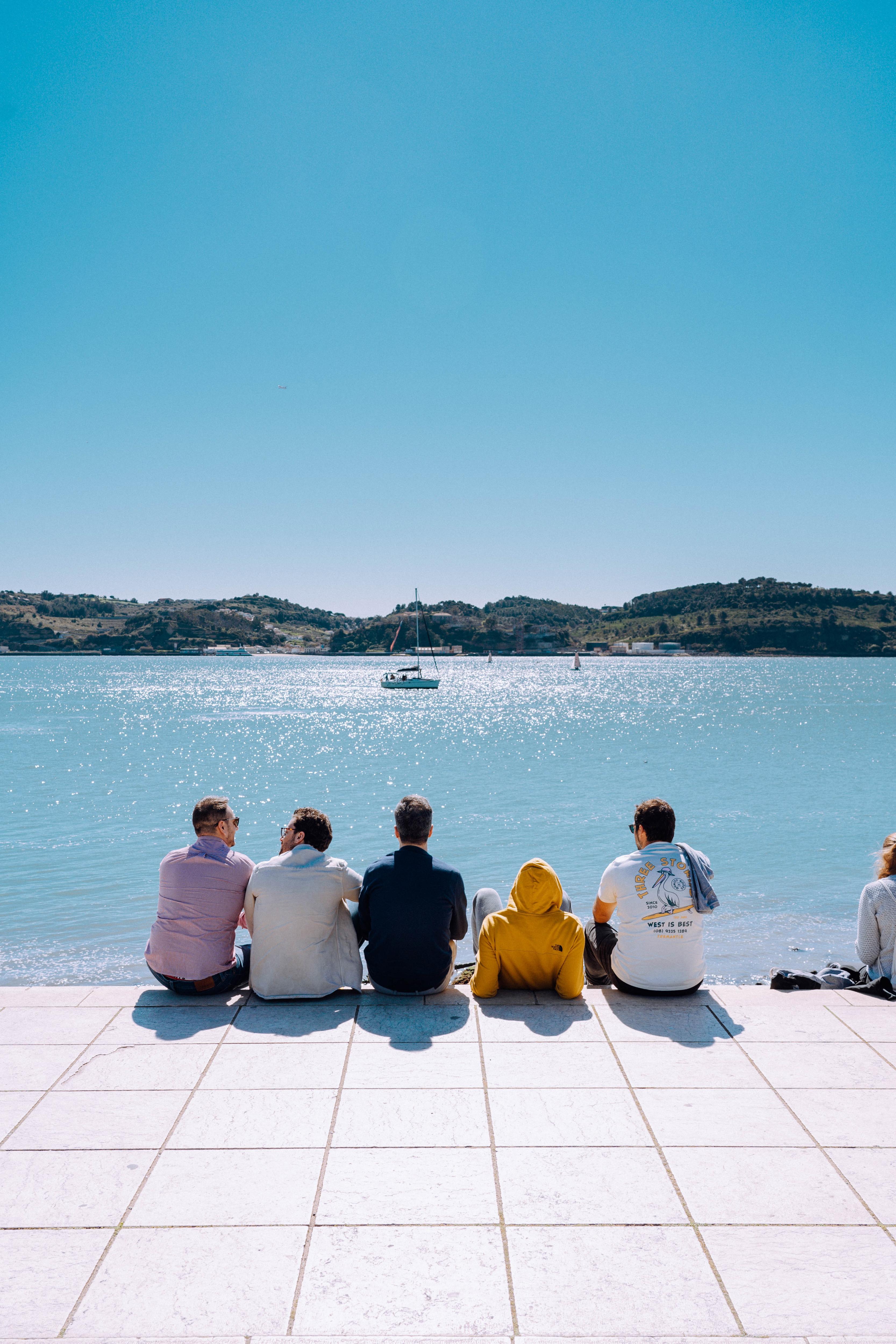 group of male friends sitting by the water