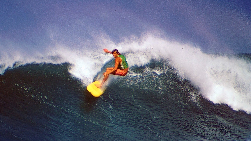 A man rides a surfboard on a large wave.