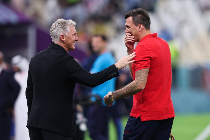 Former footballers Mario Mandzukic and Bastian Schweinsteiger laugh together before the Argentina-Croatia World Cup semifinal.