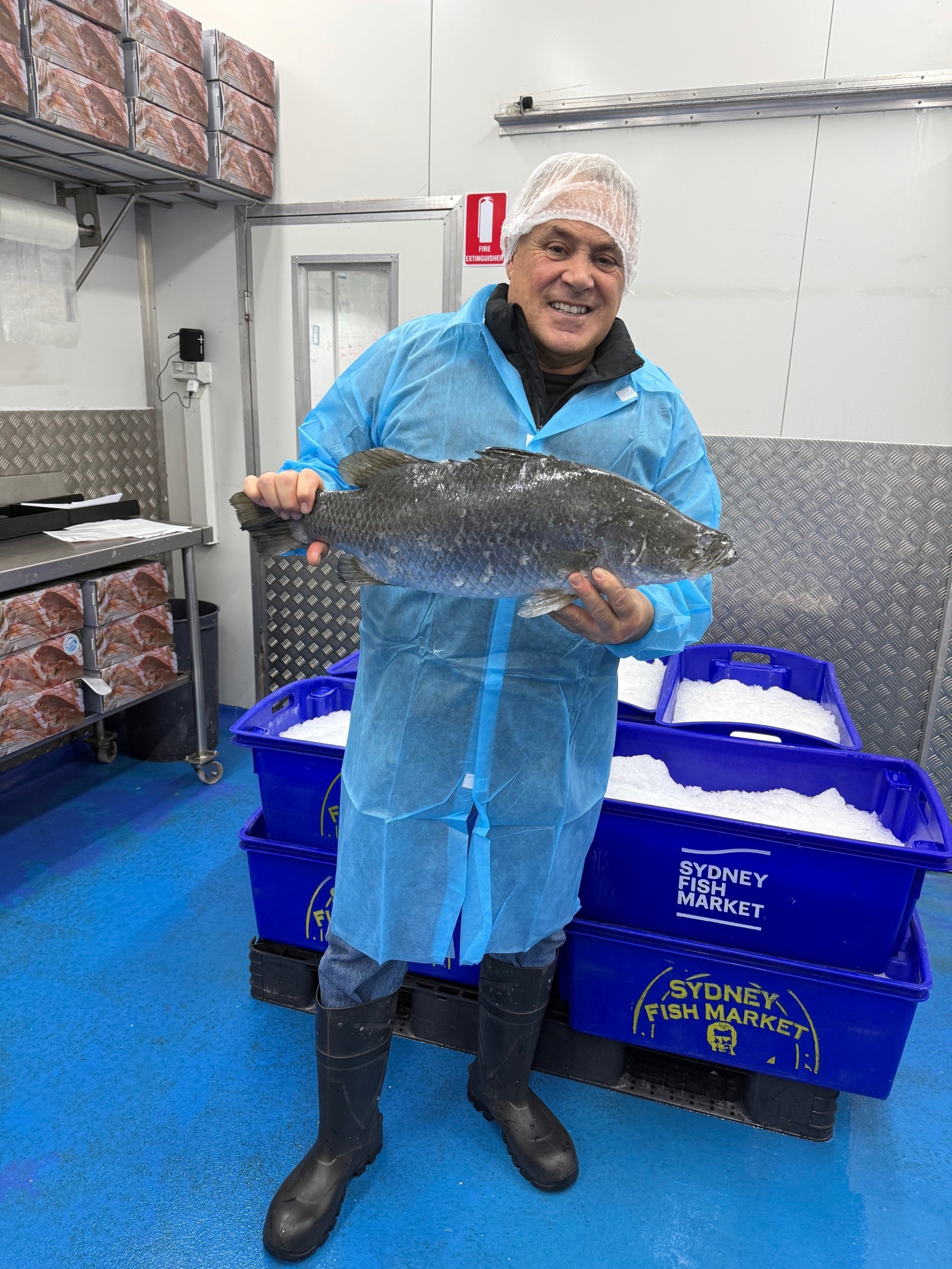 Man holding a barramundi fish in a storeroom