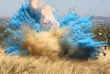 A target explodes into a cloud of blue powder.