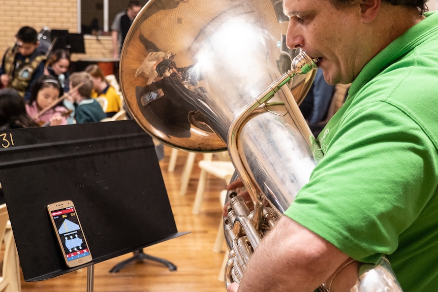 Adrian Hawkins tunes his tuba before playing.