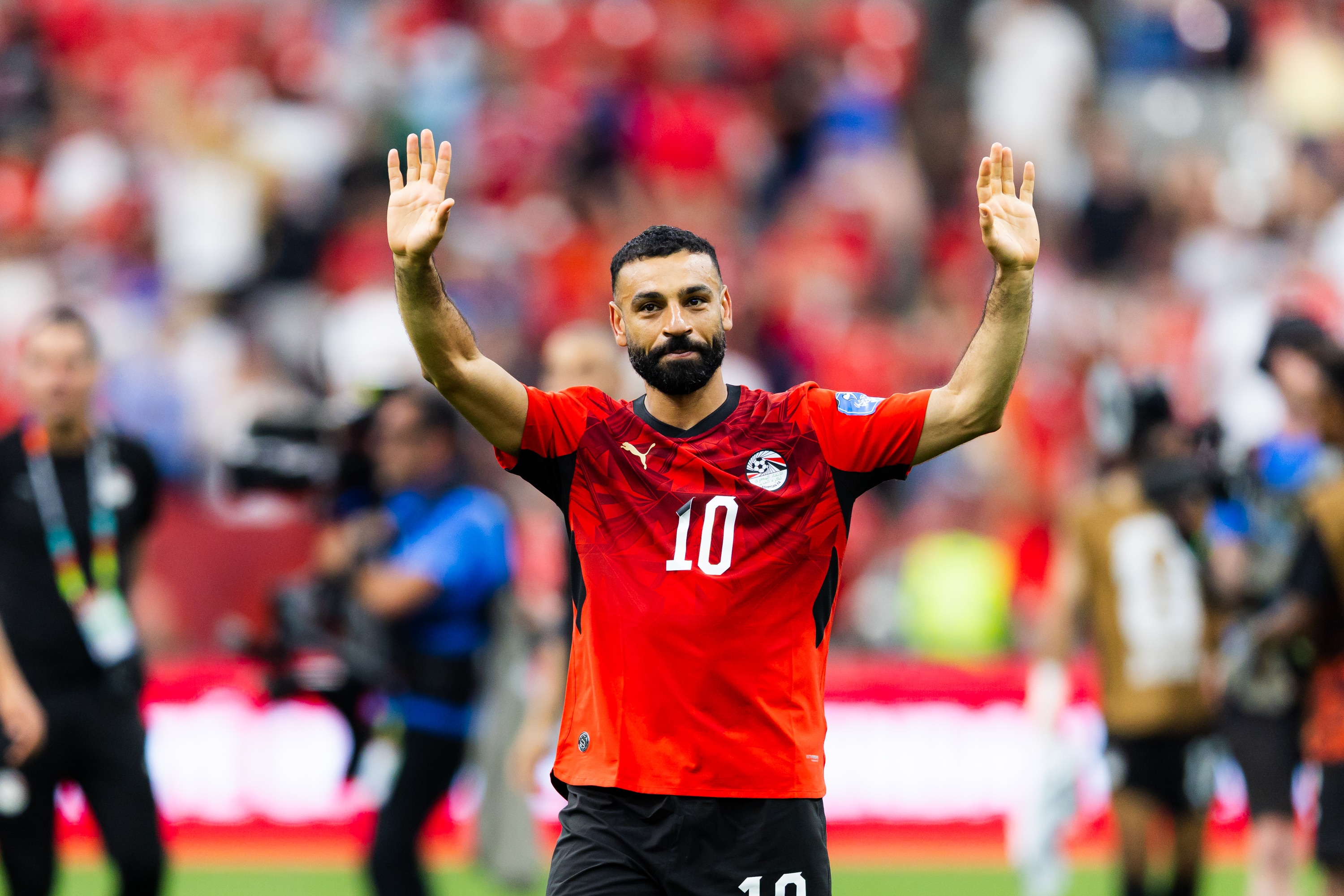 A soccer player in red waves to a crowd