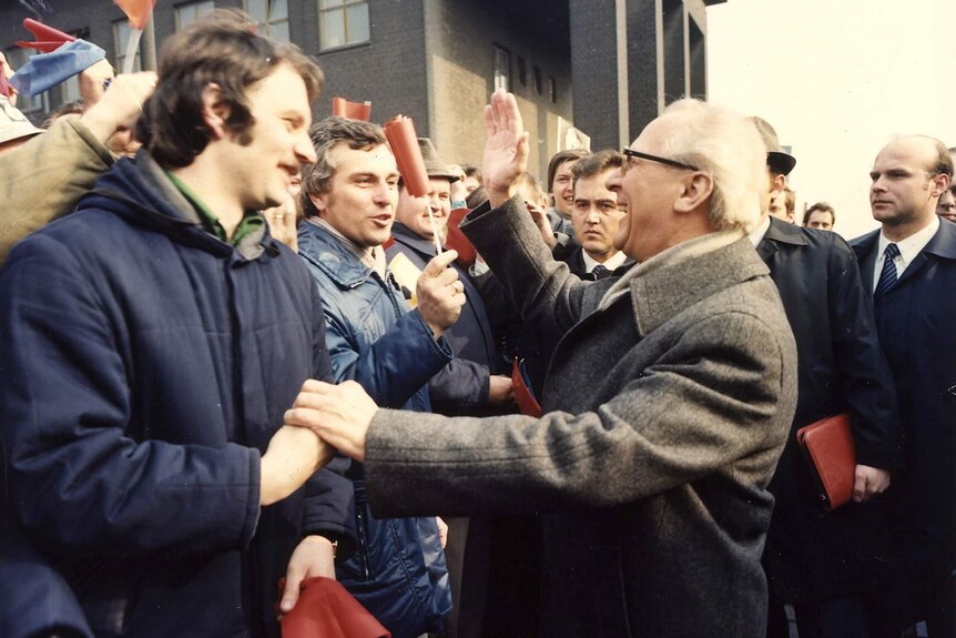 Archival image of German politician Erich Honecker embracing someone in a crowd.