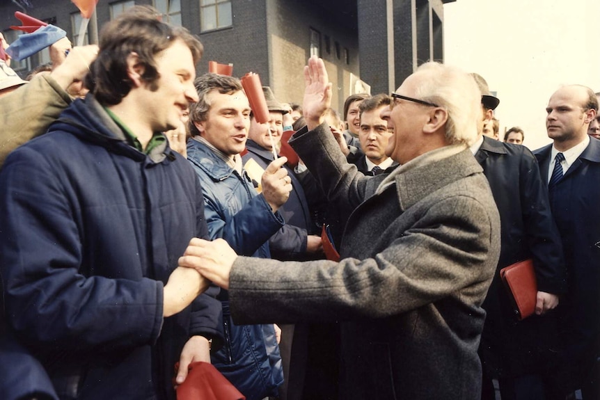 Archival image of German politician Erich Honecker embracing someone in a crowd.