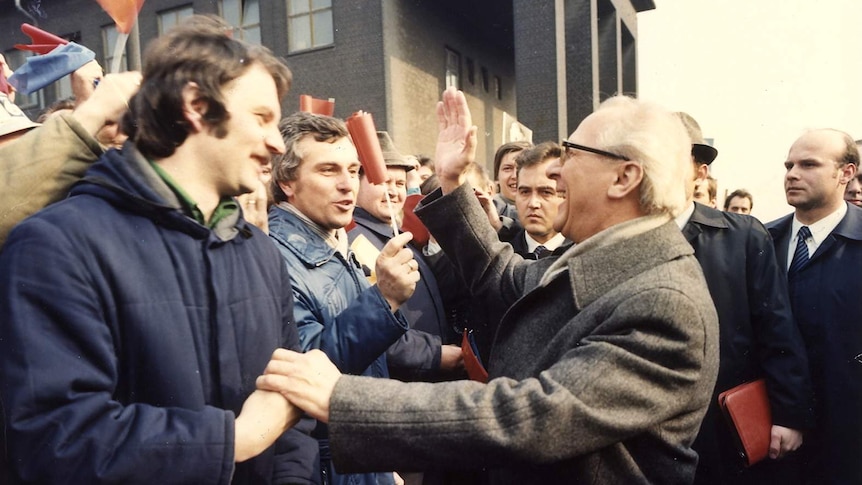 Archival image of German politician Erich Honecker embracing someone in a crowd.