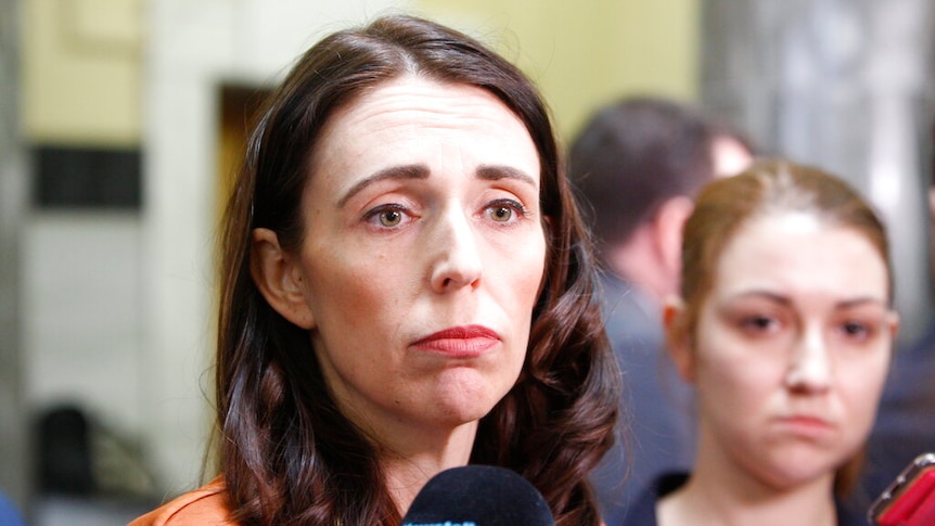 Jacinda Ardern speaks to press. There is a microphone close to her face and she has a deflated expression.