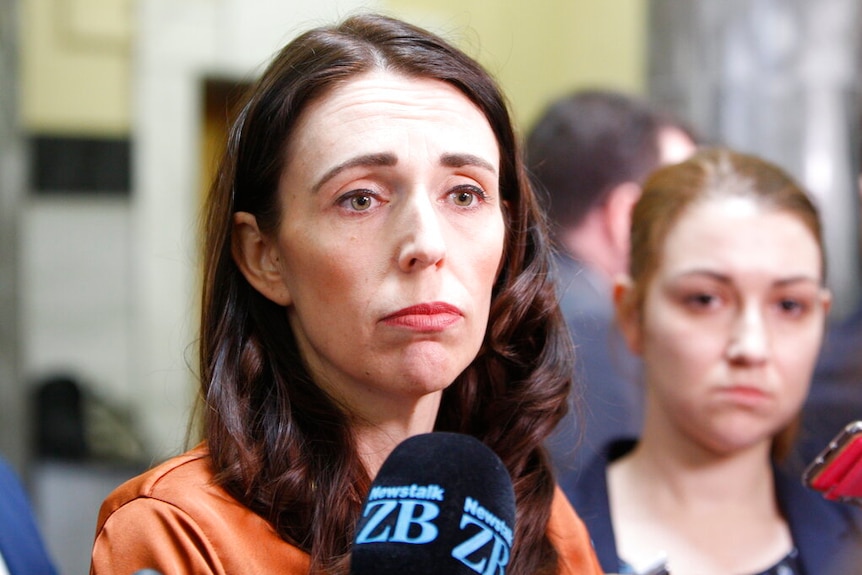 Jacinda Ardern speaks to press. There is a microphone close to her face and she has a deflated expression.