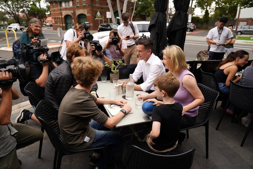 a  family sitting at a cafe with media surrounding them