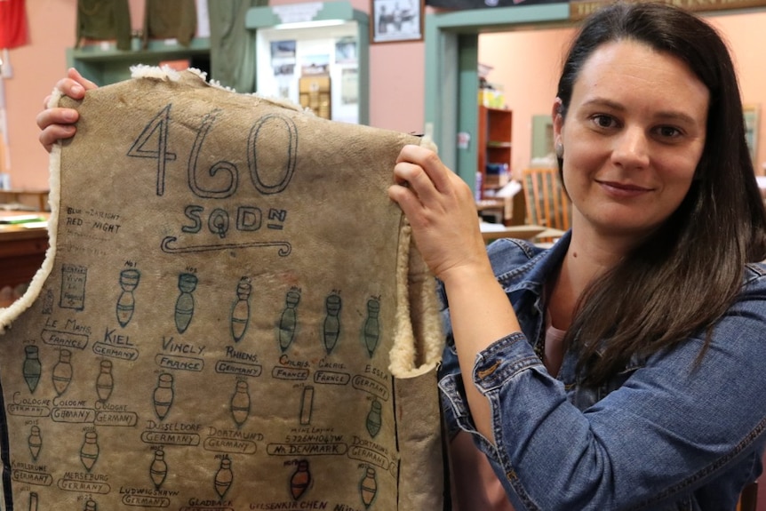 Woman on right holding sheepskin vest with drawings of bombs on it.