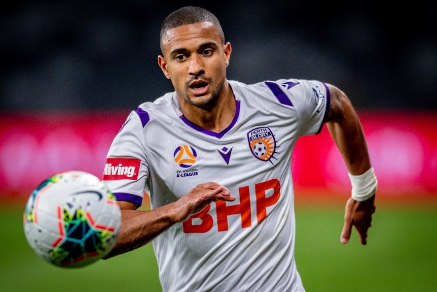 James Meredith keeps his eyes on the ball wearing a white Perth Glory top