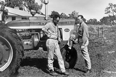 Two men stand next to a tractor.