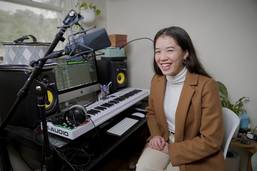 Lucy Sugerman sits next to her keyboard, surrounded by recording equipment.