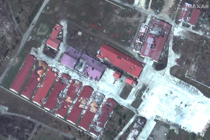 Widok z góry przedstawiający czerwone dachy budynków otoczonych terenem. 