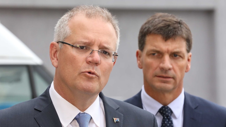 PM Scott Morrison speaks to media in Canberra as Angus Taylor, frowning, watches on.