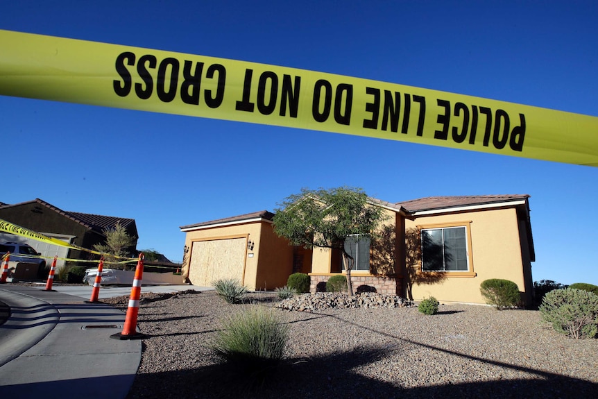 Yellow police tape in the foreground says police line do not cross, and Stephen Paddock's beige brick home in the background