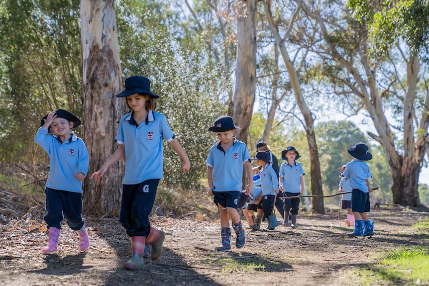 A group of young Guildford Grammar Preparatory School students in blue uniforms walk along a bush path.
