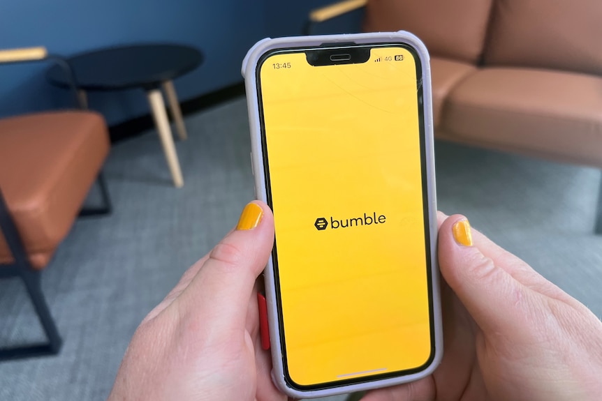 a hand opens the bumble app.